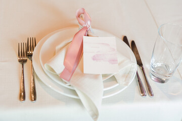 Coziness and style. Modern event design. Table setting at wedding reception. Floral compositions with beautiful flowers and greenery, candles, laying and plates on decorated table.