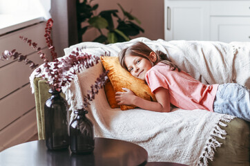 Positive smiling blonde teenage girl lying on a couch.