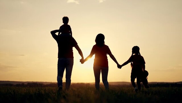 Happy family concept. People walk on grass in field. Girl with teddy bear in her hands.Group of people walk at sunset in park.Active lifestyle concept.Family in natural park.Parents with child in park
