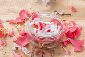 Beauty product container filled with fresh dark pink flower petals and moisturizer. Idea for natural cosmetics mock up. 