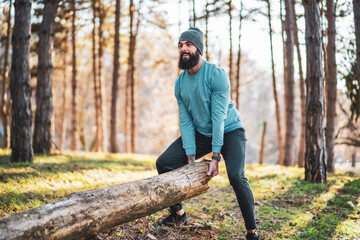 Strong sporty man is lifting tree stump .