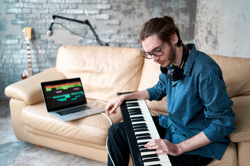 Image of male musician playing electronic piano and recording music at home studio. Concept of domestic hobby, entertainment and leisure. Young creative songwriter man  © VADL