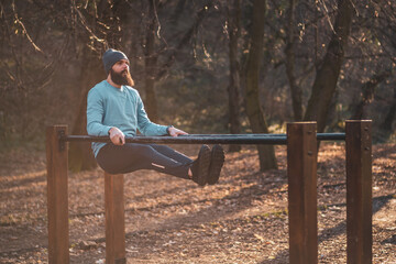 Man enjoys  exercise push- ups on parallel bars in the park.