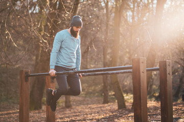 Man enjoys  exercise push- ups on parallel bars in the park.