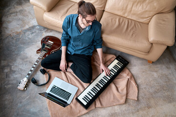 Image of male musician playing electronic piano and recording music at home studio. Concept of domestic hobby, entertainment and leisure. Young creative songwriter man 