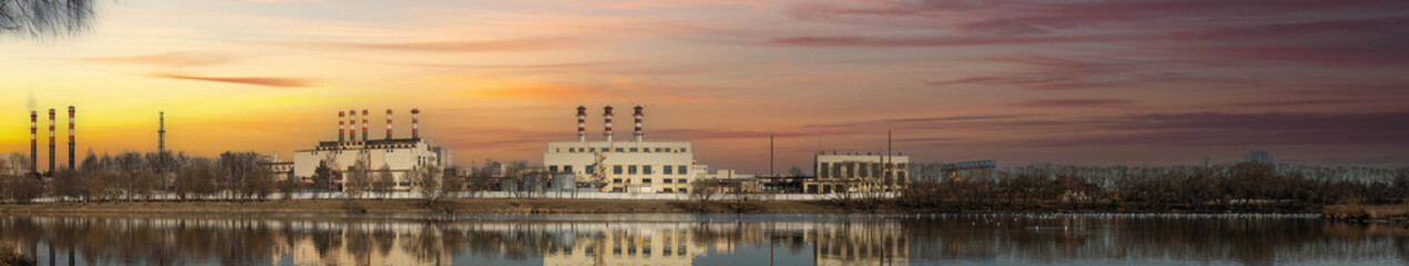 Fototapeta na wymiar large industrial zone in the city, factories and nuclear power plants near the river at sunset.