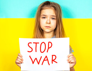 The girl holds a STOP WAR poster in her hands against the background of the Ukrainian flag. Place for inscription text