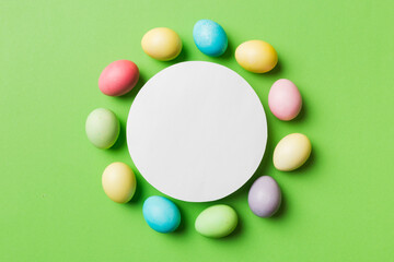 round frame multicolored Easter eggs with white blank paper on a brown background, close-up, space for text, blank for design, selective focus, tinted image