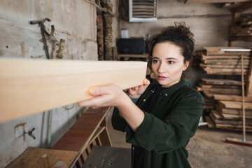 Carpenter checking blurred wooden plank in workshop.