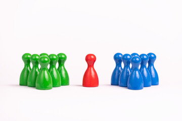 one red game piece between a group of green and a group of blue toy figures, white background,...