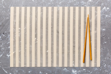 Two chopsticks and bamboo mat on cement background. Top view, copy space