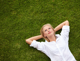 So much to ponder.... High angle shot of an attractive young woman relaxing on a grassy field and...