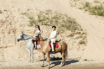 a guy and a girl on horseback on the river bank