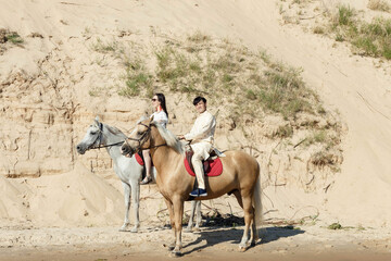 a guy and a girl on horseback on the river bank
