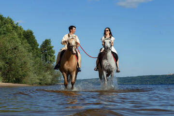 Fototapeta na wymiar a guy and a girl on horseback on a river on a sunny day