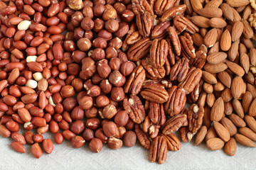 Raw peeled peanuts, hazelnuts, pecans, almonds and walnuts on a linen cloth. Closeup. Macro