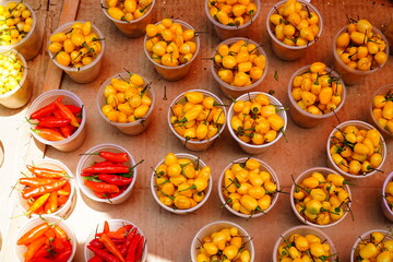 Small yellow chili peppers Pimenta Cheiro (capsicum chinense, adjuma) at a street market in Belem, Brazil. At the side some bowls of Brazilian red chili peppers Malagueta (capsicum frutescens).