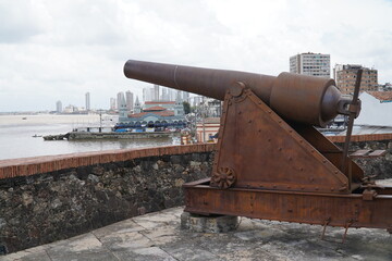 Cannon in the fort of the castle (Forte do Castelo), behind it the old Ver-O-Peso market and in the background modern skyscrapers, Belem, state of Para, Brazil.