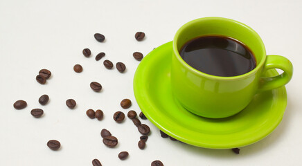 Black coffee and beans with mug on green on white background.