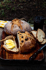 Round loaf of Irish soda bread sliced with slice of bread spread with butter and honey on a wooden dipper