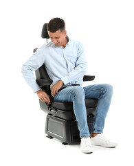 Young man fastening in car seat on white background