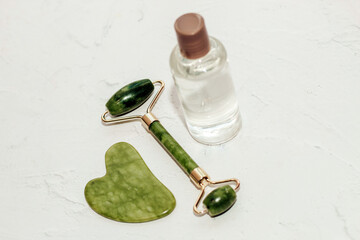 massage stone jade gouache scraper and facial roller with cosmetic cream.