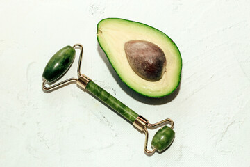 Green ripe avocado with jade gouache scraper and rollerball on light background.