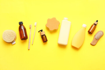 Different cosmetic products and bath accessories on yellow background