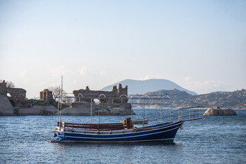 Lake Bafa fishing boat scenic view of ruins of Herakleia (Latmos) ancient city. Milas, Turkey.