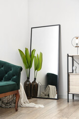 Vase with palm leaves and mirror in stylish living room interior