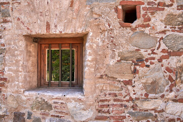 Fototapeta na wymiar small wooden window with metal fence in a old rustic brick wall in a town in Argentina. Horizontal