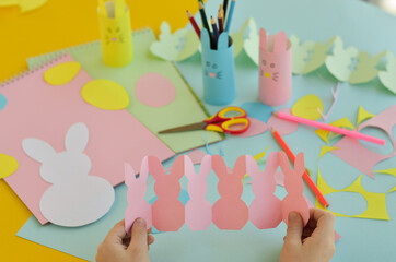 a close-up of a schoolboy who holds a garland of pink bunnies in his hands. Easter crafts, craft...