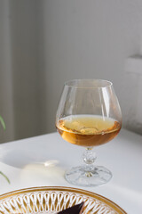 brandy snifter on white reflective table with white background by window