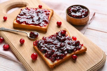 Toasts with tasty lingonberry jam on light wooden background