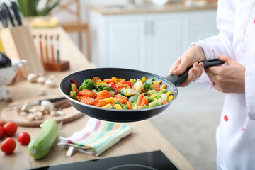 Female chef frying tasty vegetables in kitchen, closeup
