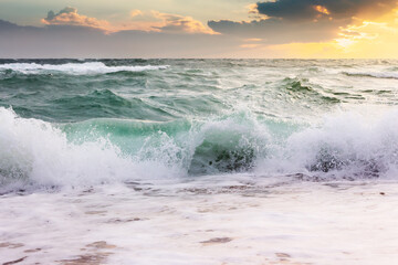 seascape with waves crashing the beach at sunrise. beautiful summer scenery at the sea in morning light