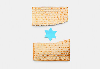 Torn Jewish flatbread matza for Passover with paper David star on light background