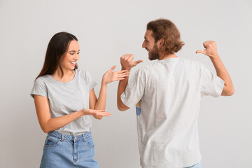 Young couple in stylish t-shirts on light background