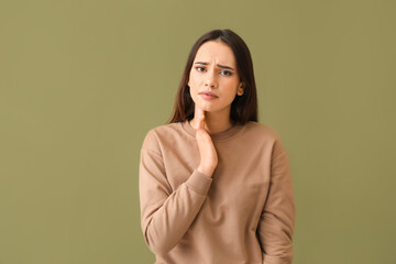Young woman suffering from sore throat on color background