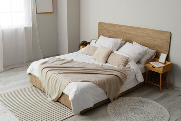 Fototapeta na wymiar Comfortable bed and nightstands near light wall