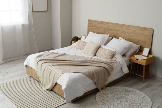 Comfortable bed and nightstands near light wall