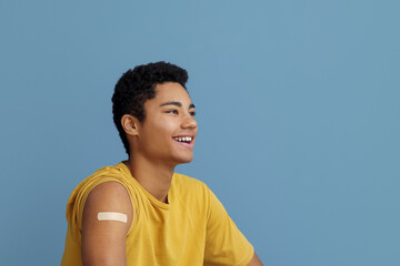 Young African-American man with applied medical patch on blue background
