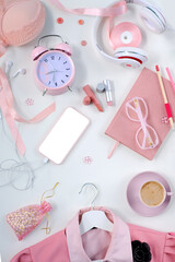 Fototapeta premium womens stylish accessories, smartphone with blank screen, glamorous set in pink shades, flat lay, copy background, womens clothing, alarm clock, lipstick, coffee cup, good morning concept, female life
