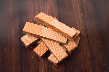 Stacked delicious chocolate wafers, side corner photo on wooden background.