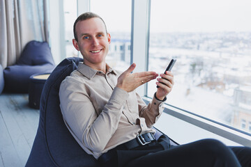 A businessman communicates with his clients by phone while sitting in a modern office workspace. Focused businessman sits alone in a modern workspace.