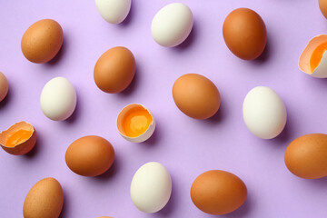 Cracked and whole chicken eggs on purple background