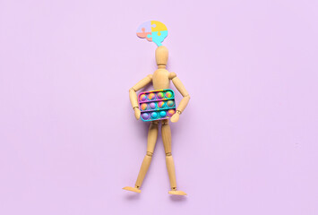 Wooden mannequin with pop it fidget toy and puzzle pieces on lilac background