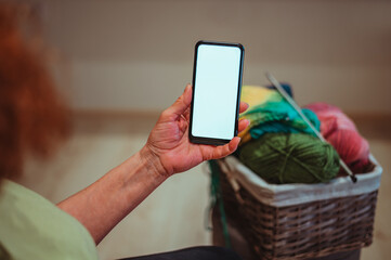 Close up of a wrinkled hands of a senior woman holding a smartphone