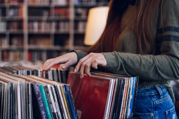 Deurstickers Muziekwinkel Woman hands choosing vinyl record in music record shop