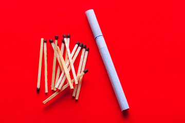 Obraz premium Tobacco cigarette and matches , red background 